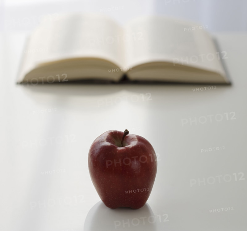 Apple in front of open book.