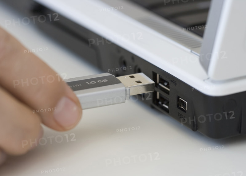 Man plugging USB stick into laptop.