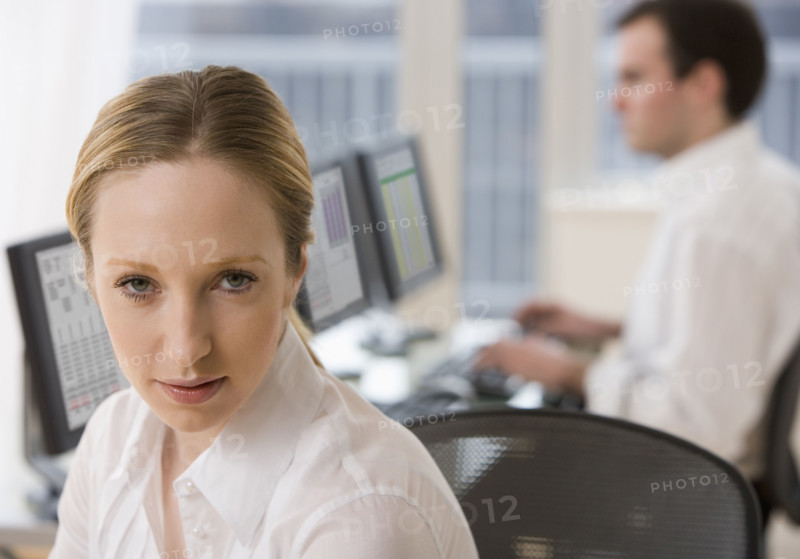 Businesswoman with co-worker in background.