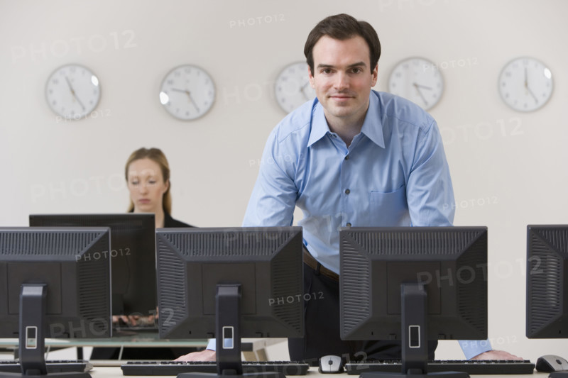 Businessman behind row of computers.