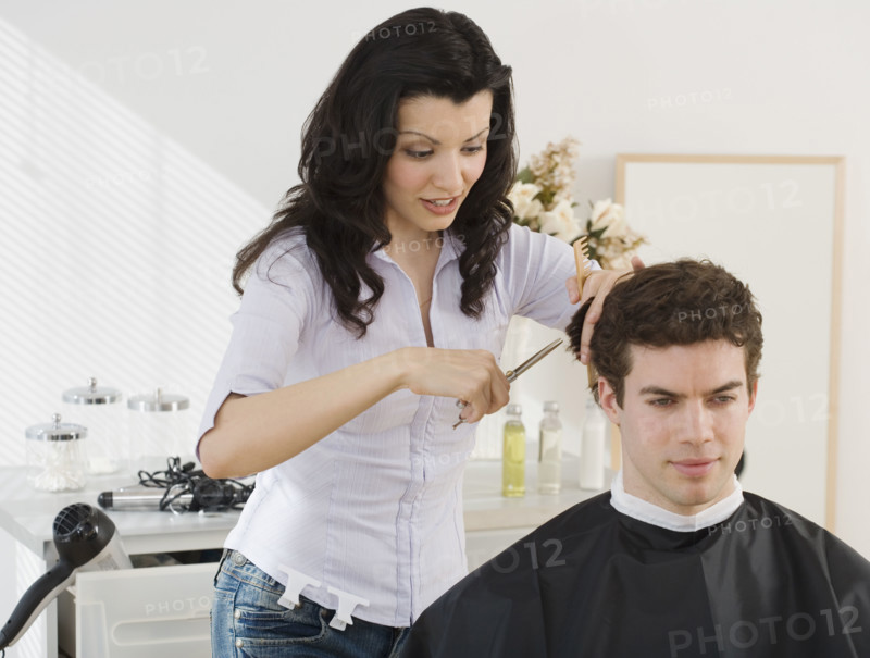 Female hair stylist cutting man’s hair.