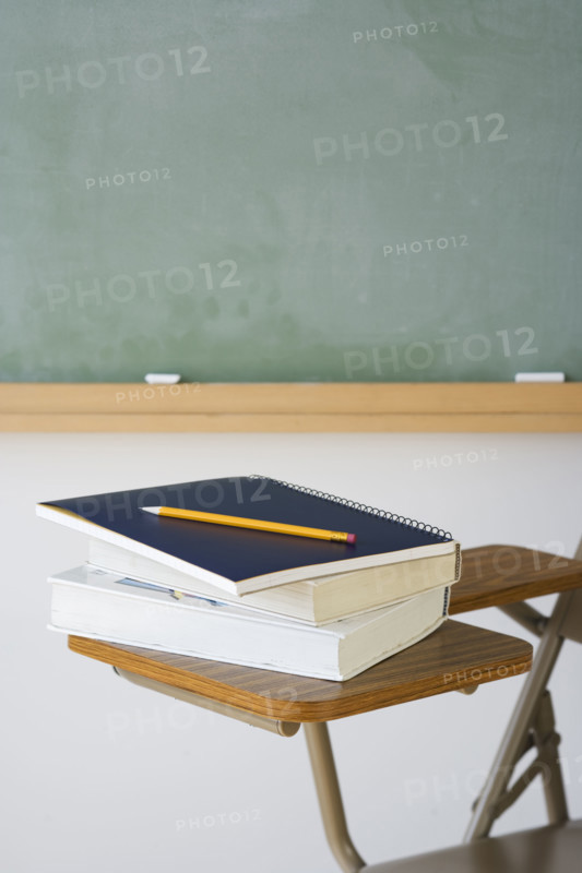 Books and pencil on desk in classroom.