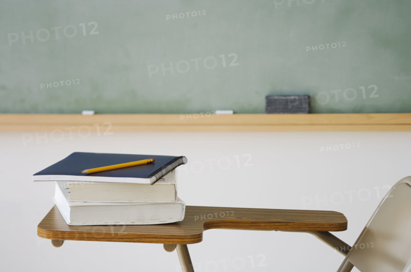 Books and pencil on desk in classroom.