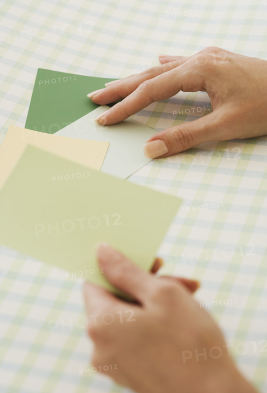 Close up of woman comparing paint swatches.