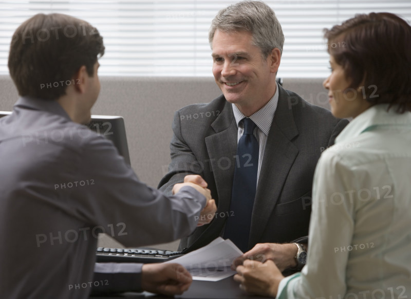 Businessman shaking hands with couple.