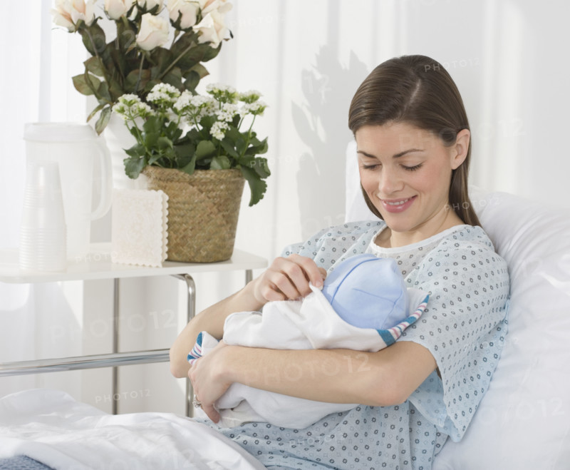 Mother smiling at newborn baby in hospital.