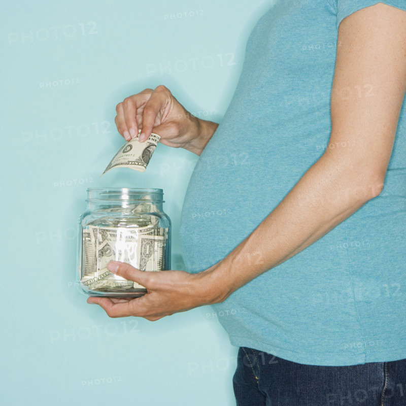 Pregnant woman putting money in jar.