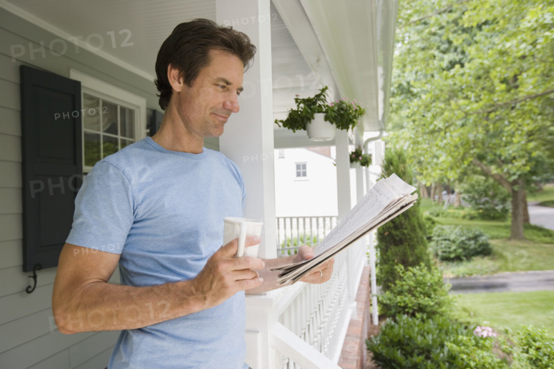 Man reading newspaper on porch.