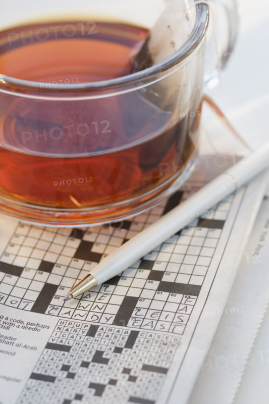 Close up of crossword puzzle and tea.