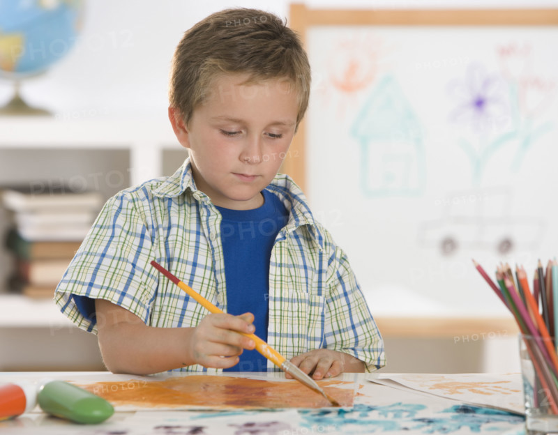 Boy painting at table.