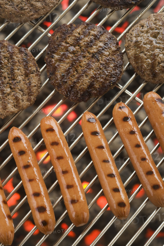 Hamburgers and hot dogs cooking on grill.