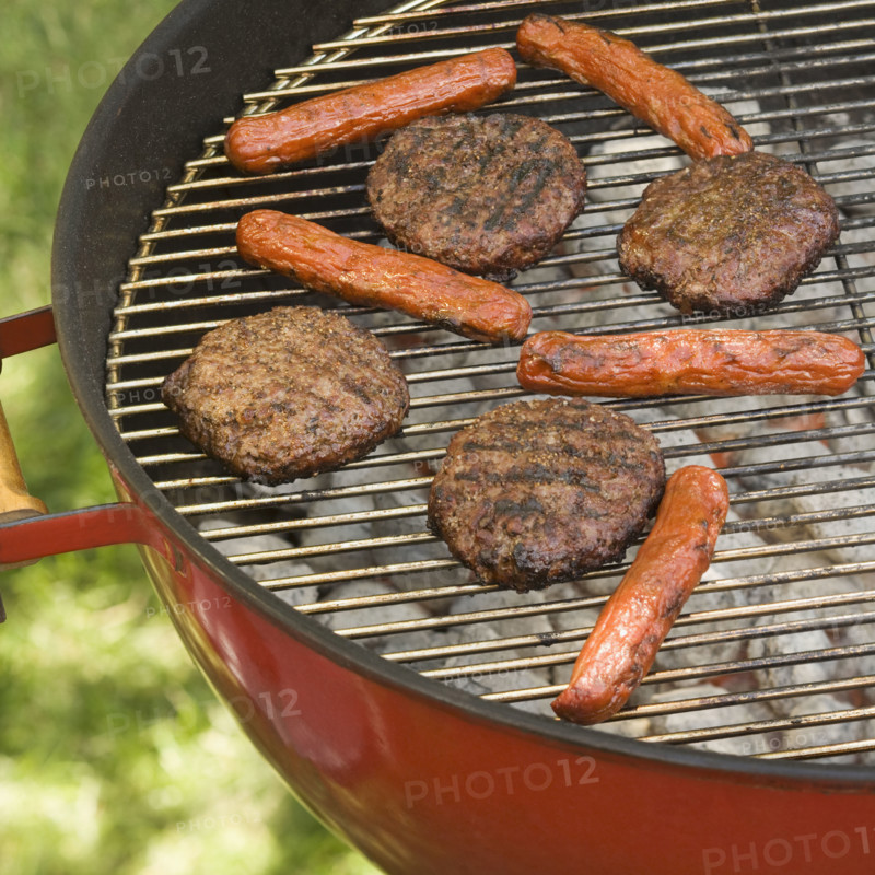 Hot dogs and hamburgers cooking on grill.
