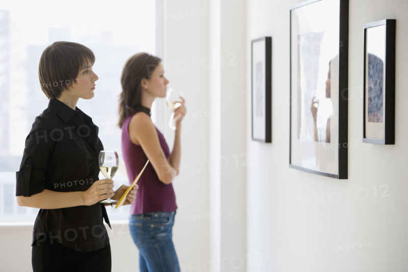 Two women looking at artwork in gallery.