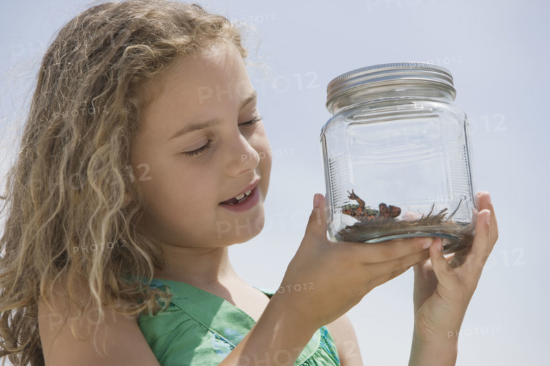 Girl looking at reptile in jar.