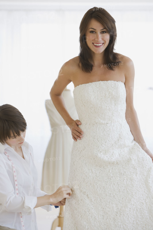 Bride having dress fitted.