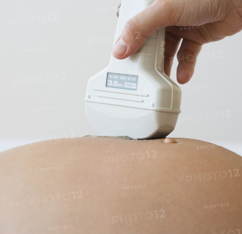 Ultrasound wand on pregnant woman .