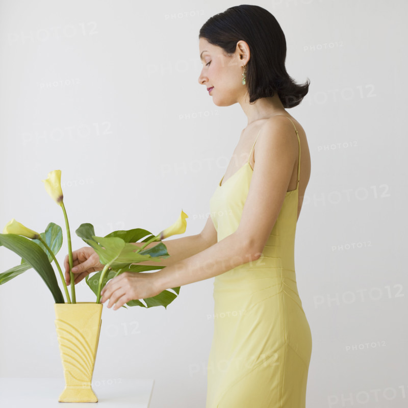 Woman arranging flowers in vase.