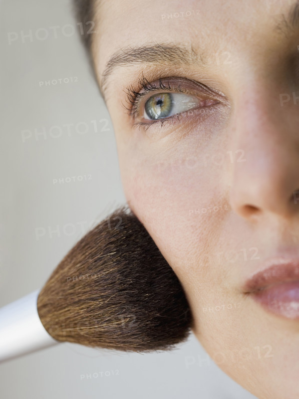 Woman applying make up with brush.