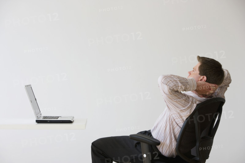 Businessman with hands behind head.