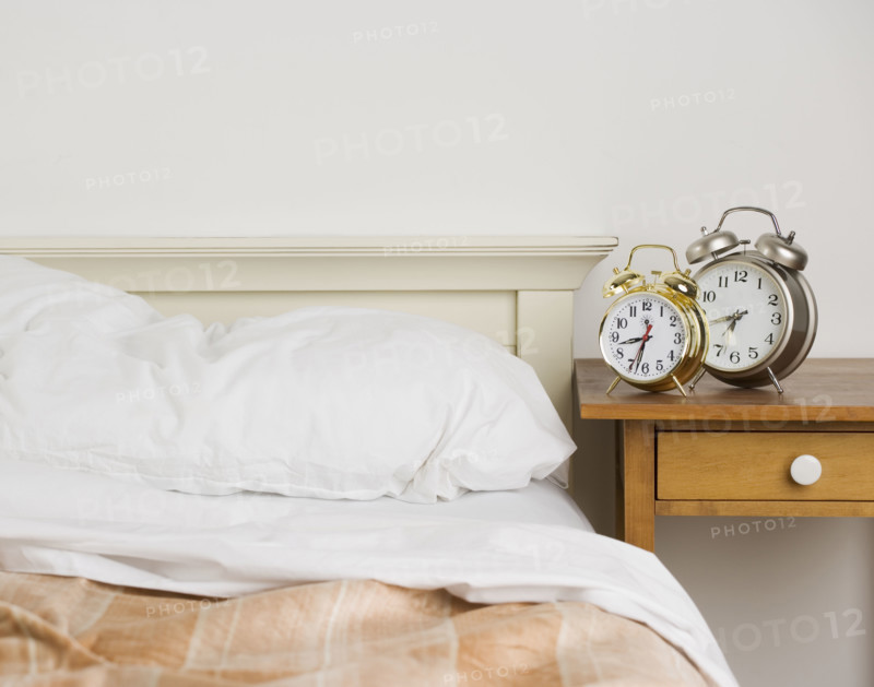 Unmade bed with alarm clocks. Date : 2006