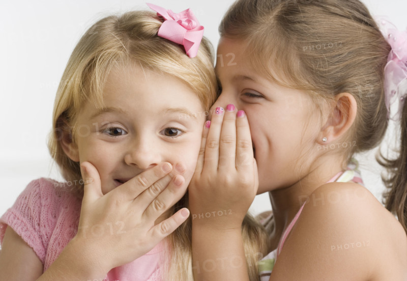 Young girl telling sister a secret. Date : 2006