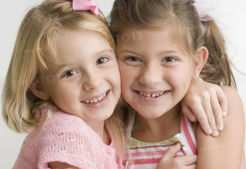 Two young sisters hugging and smiling. Date : 2006