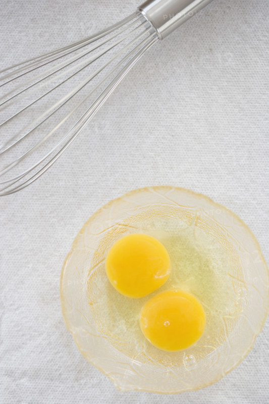 High angle view of whisk next to eggs in bowl. Date : 2006