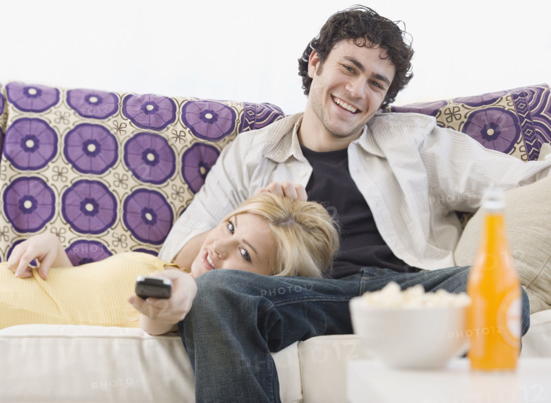 Couple watching television on sofa. Date : 2007