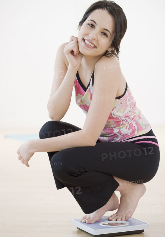Portrait of woman crouching on bathroom scale. Date : 2007