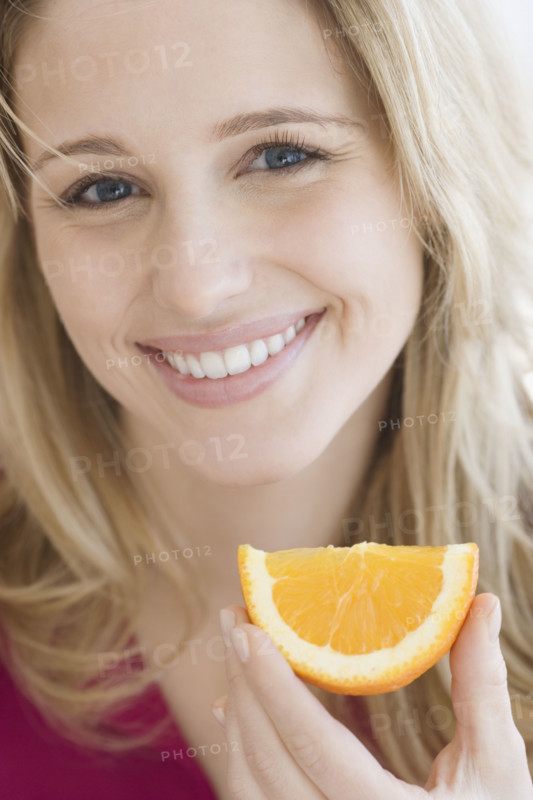 Close up of woman holding orange wedge. Date : 2007