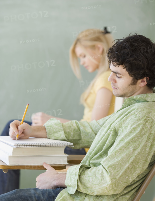 Man writing at desk in classroom. Date : 2007