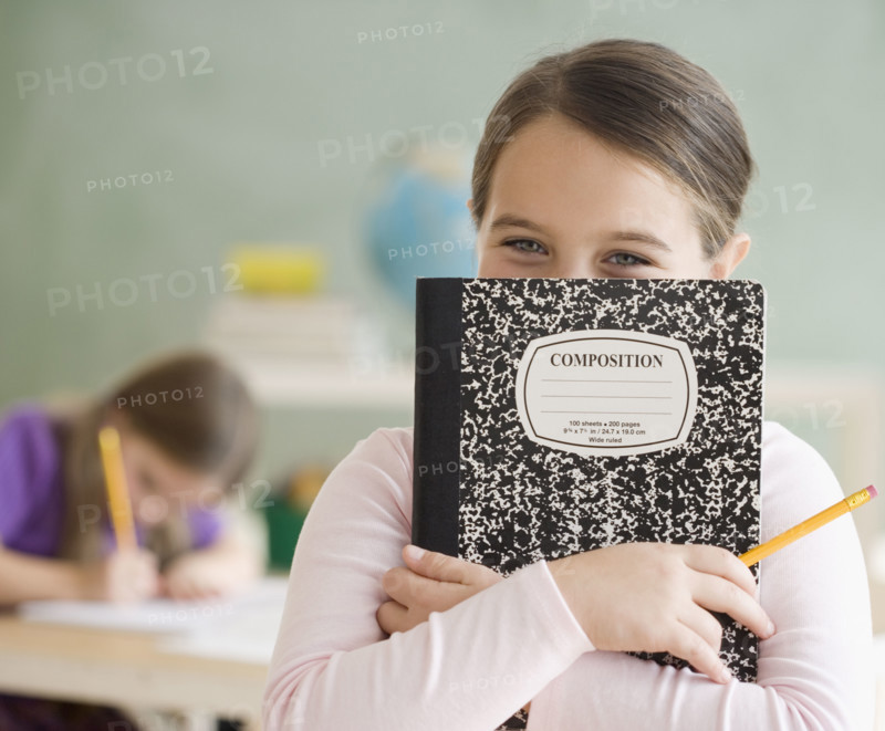 Girl holding notebook in front of face. Date : 2006