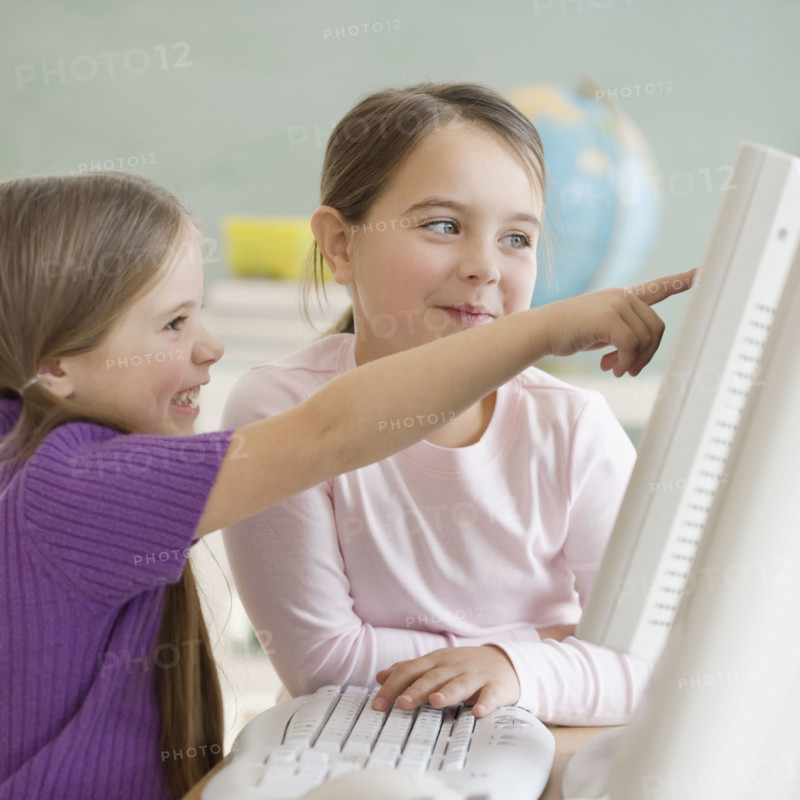 Two girls looking at computer in classroom. Date : 2006