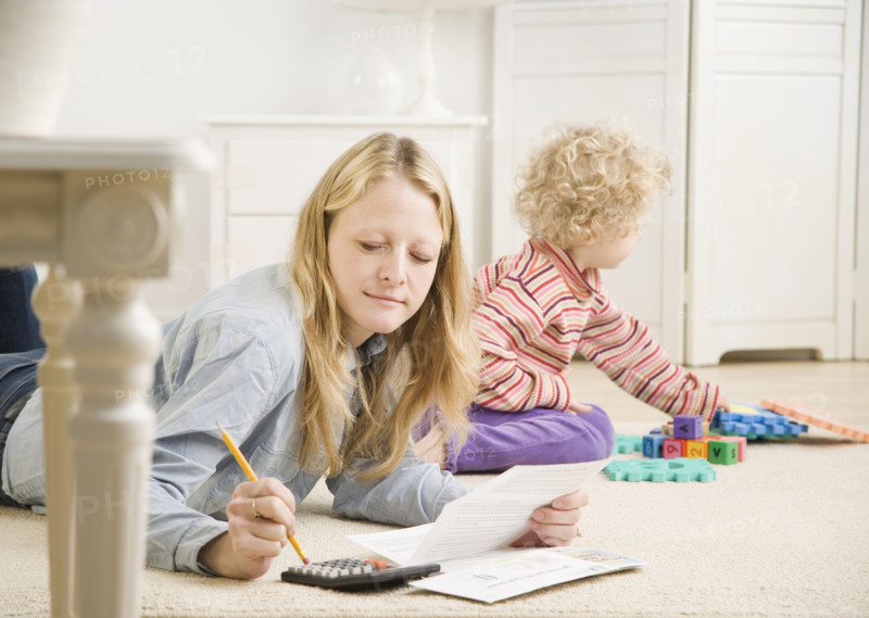 Mother working on calculator while child plays. Date : 2006