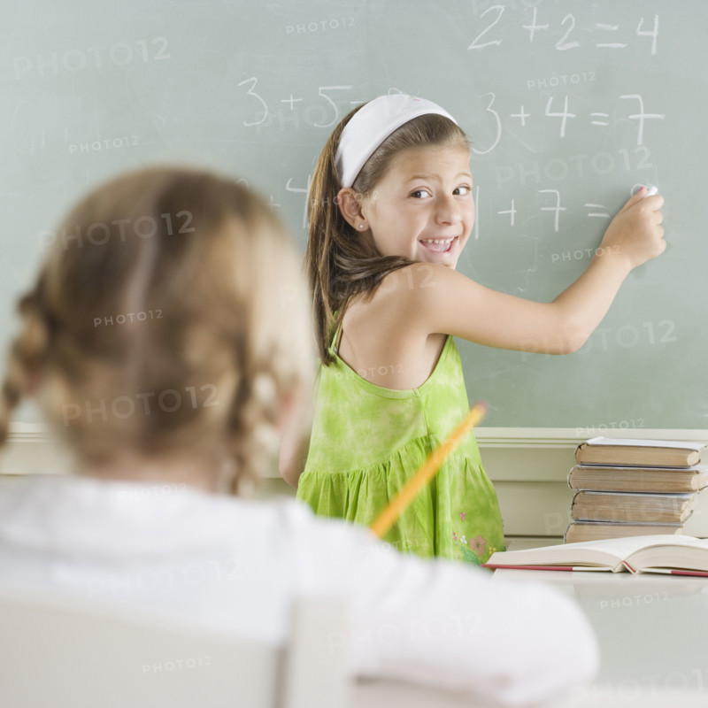 Girl writing on blackboard and smiling. Date : 2006