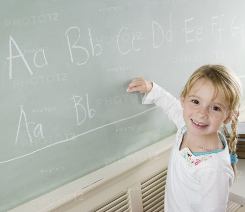 Girl writing on blackboard and smiling. Date : 2006