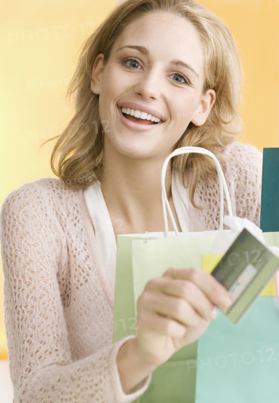 Woman with shopping bags holding credit card   . Date : 2006