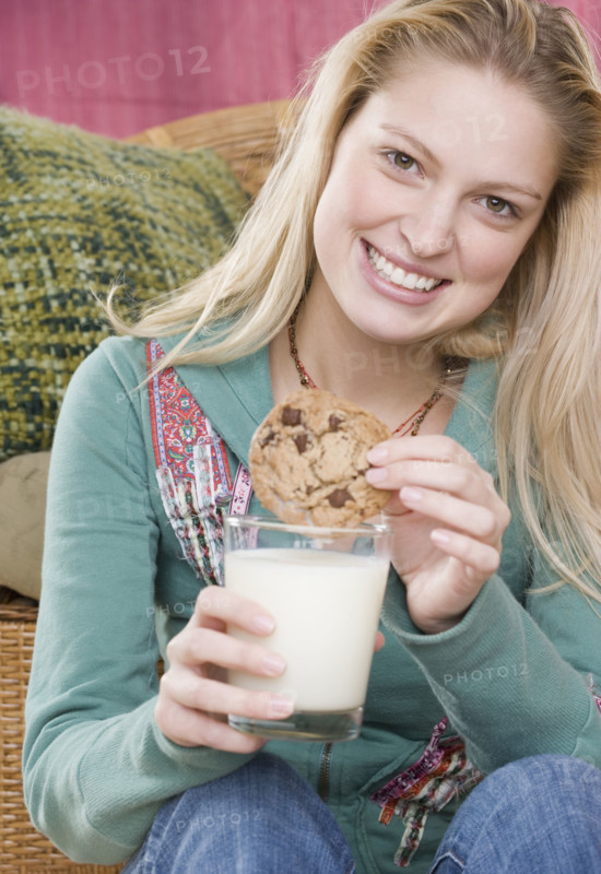 Young woman enjoying a cookie and milk. Date : 2006