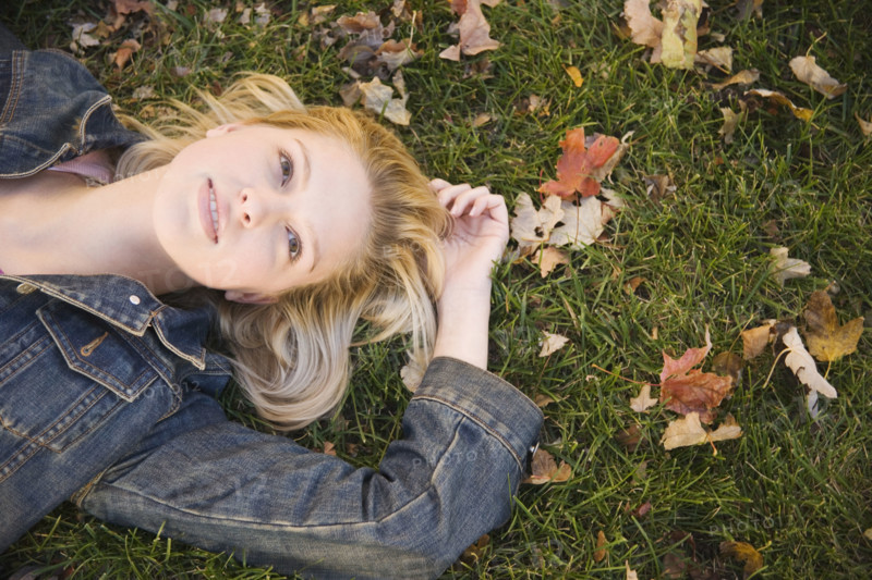Woman lying in grass on a fall day. Date : 2006