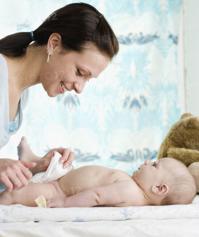 Mother changing baby’s diaper. Date : 2006