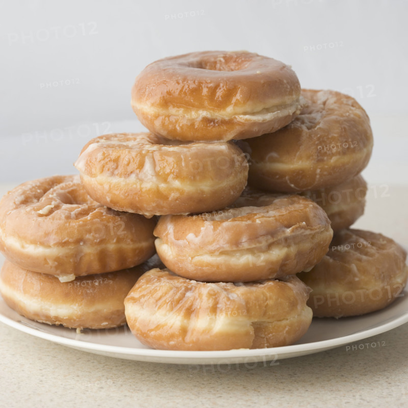 Pile of glazed donuts on plate. Date : 2006