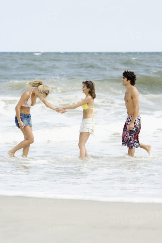 Friends standing in ocean surf. Date : 2007