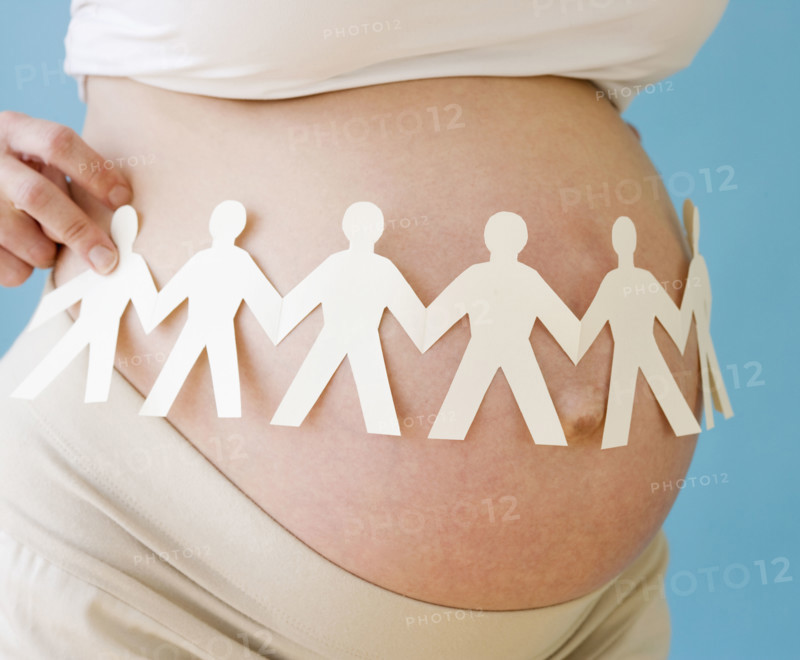 Pregnant woman holding paper dolls around belly. Date : 2007