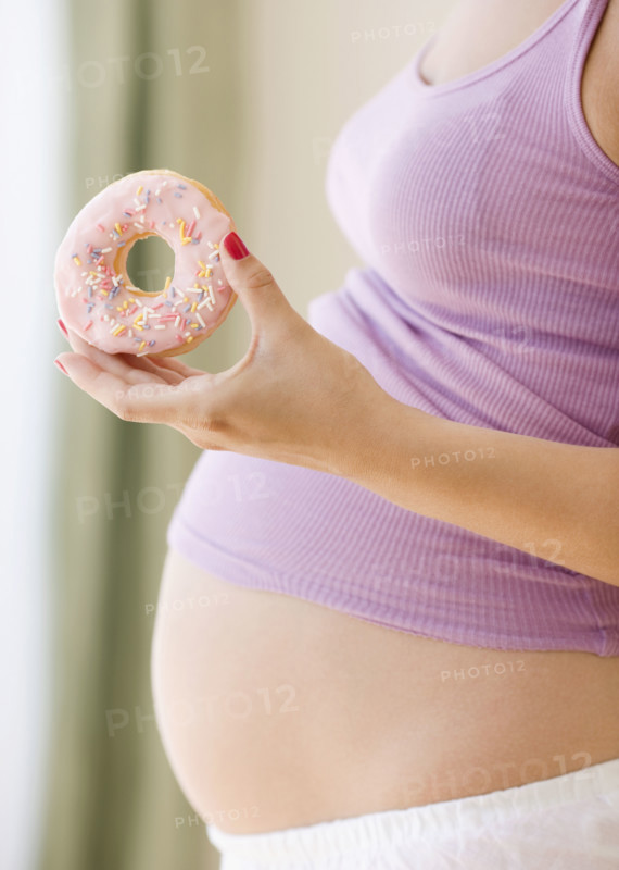 Pregnant woman holding donut. Date : 2007