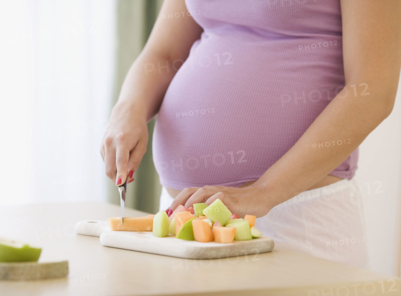 Pregnant woman chopping fruit. Date : 2007