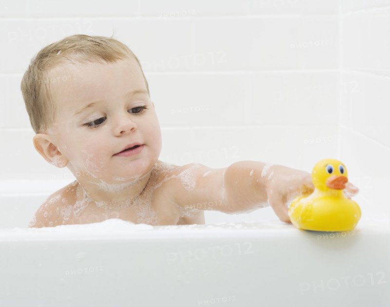 Baby playing with rubber duck in bath. Date : 2007