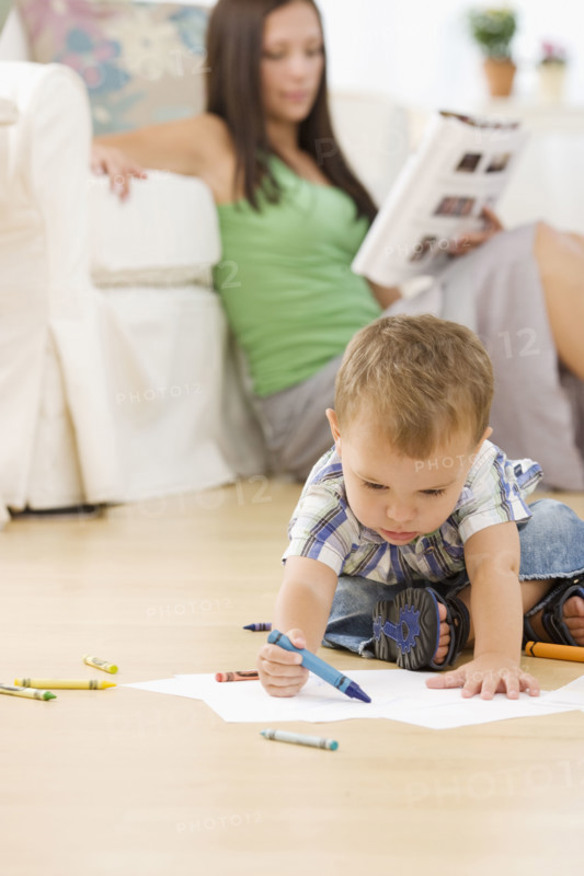 Mother reading while baby colors. Date : 2007