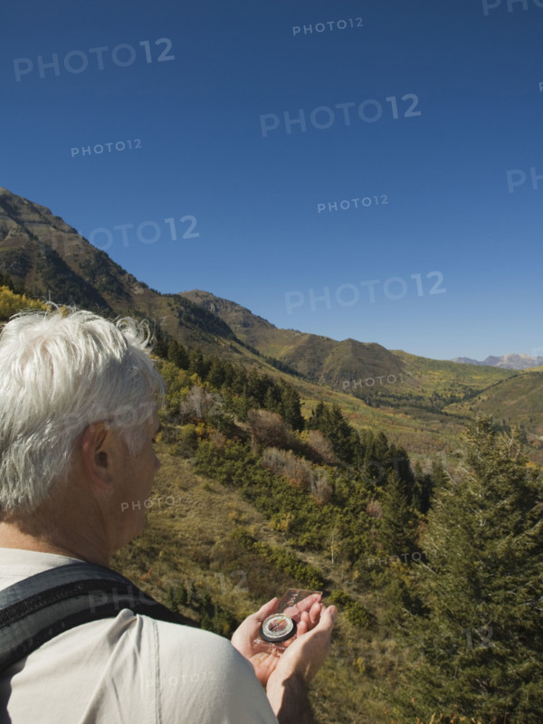 Senior man holding compass, Utah, United States. Date : 2007