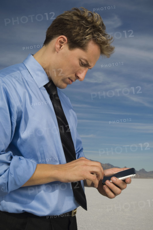 Businessman dialing cell phone, Salt Flats, Utah, United States. Date : 2007