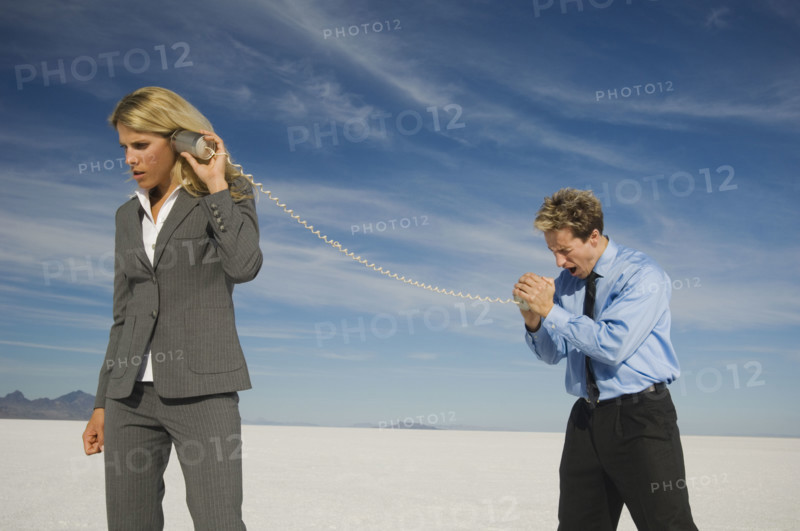 Businesspeople talking with can and string phone, Salt Flats, Utah, United States. Date : 2007